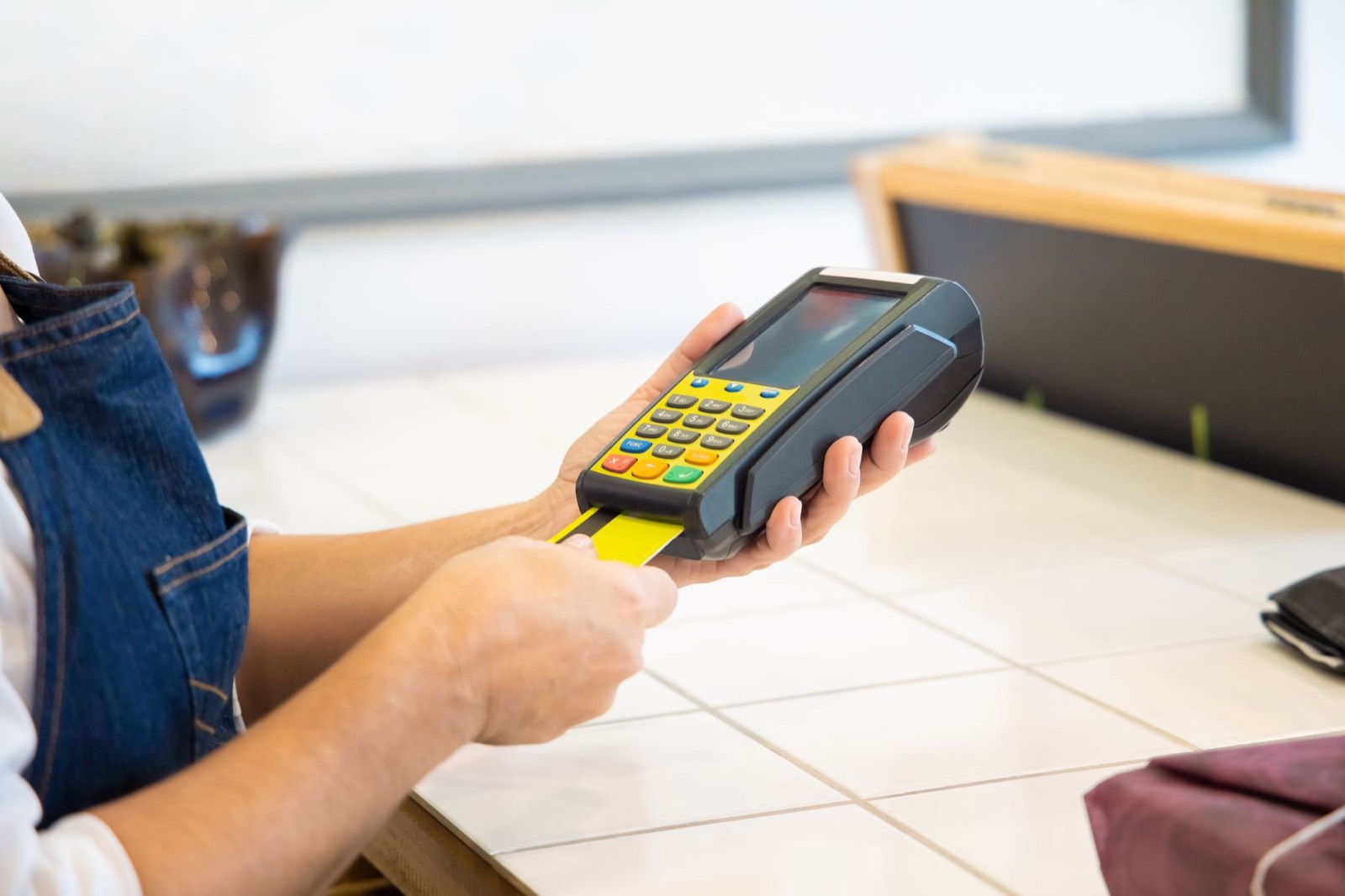 Client réglant ses achats par carte bancaire sur un terminal de paiement au comptoir d'une boutique